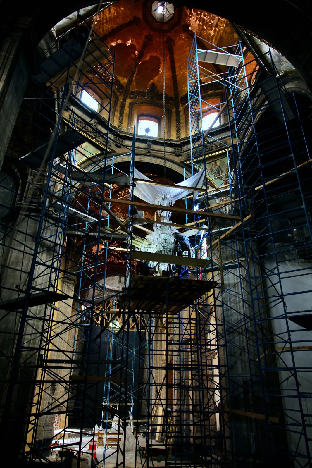 Restauradores trabajando sobre andamios en el interior de la cúpula de un templo