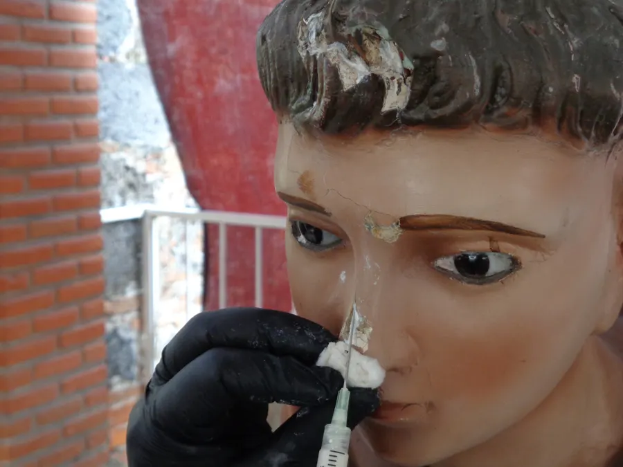 Restauradora reintegrando el rostro de una escultura policromada